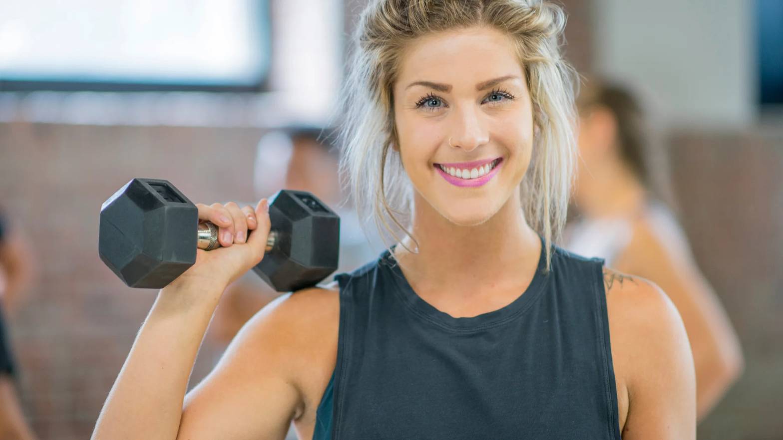 A woman happily lifting a dumbbell