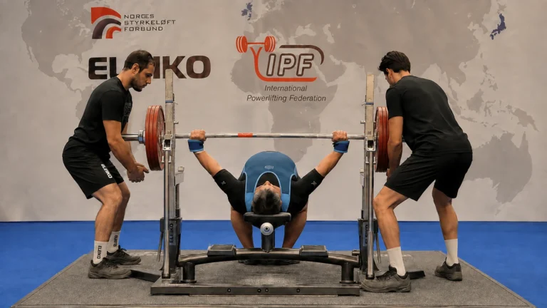 Askar Shokhanov completing a 340-kilogram equipped bench press with two side spotters.