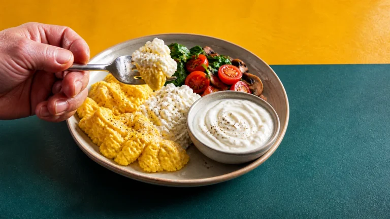 Breakfast plate with scrambled eggs, cottage cheese, vegetables and a small bowl of yogurt.