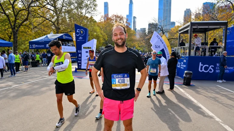 Facebook-derived portrait of Daniel Humm in a marathon finish area, wearing a black shirt and pink shorts.