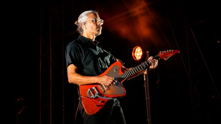 Facebook-derived portrait of Dave Depper playing an orange electric guitar under warm stage lighting.
