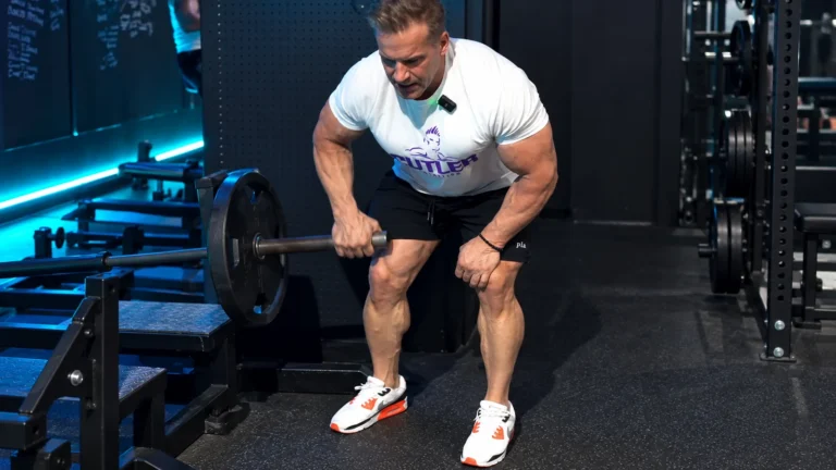 Jay Cutler performs a one-arm Meadows row in a gym, with his free hand braced on his thigh.