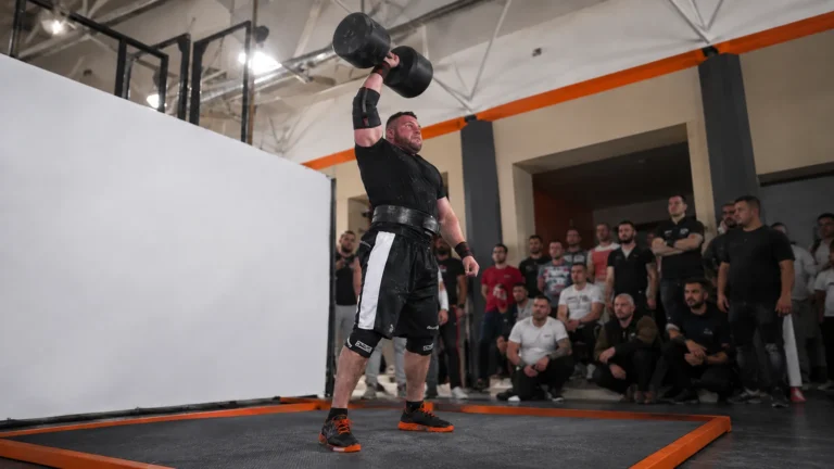 Oleksii Novikov pressing a 100-kilogram giant dumbbell overhead during a strongman record attempt.