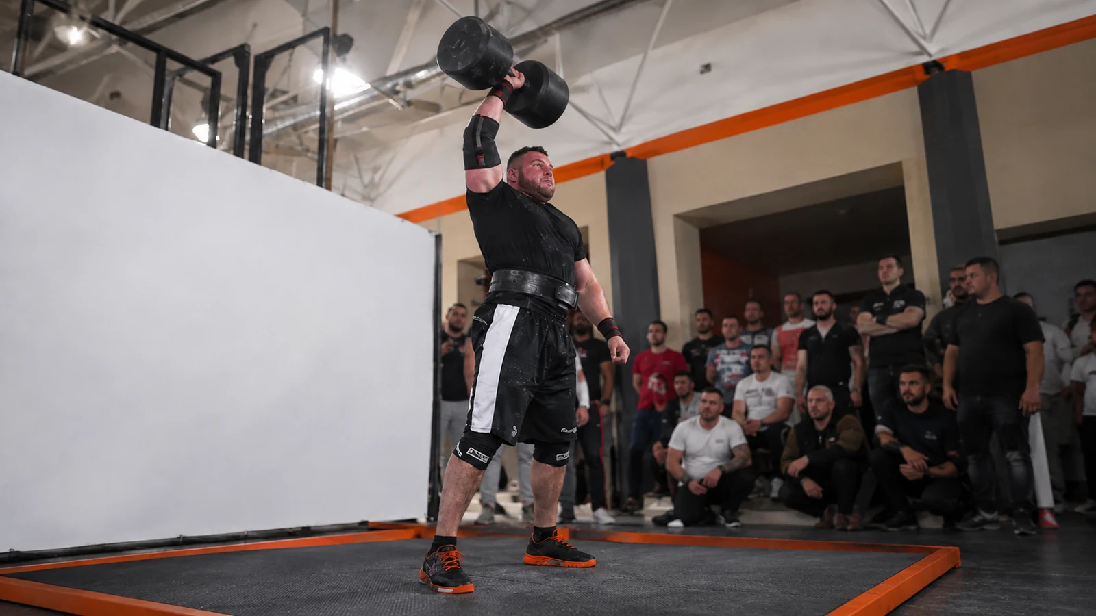 Oleksii Novikov pressing a 100-kilogram giant dumbbell overhead during a strongman record attempt.