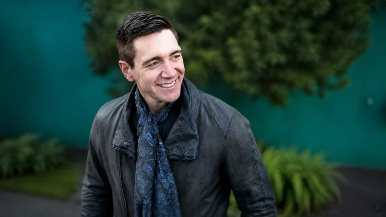 Oliver Phelps in a dark jacket and scarf in an outdoor portrait