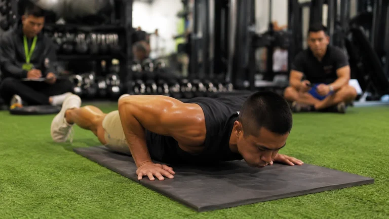 Tommy Vu lowers his chest to a mat during a judged burpee record attempt on green turf