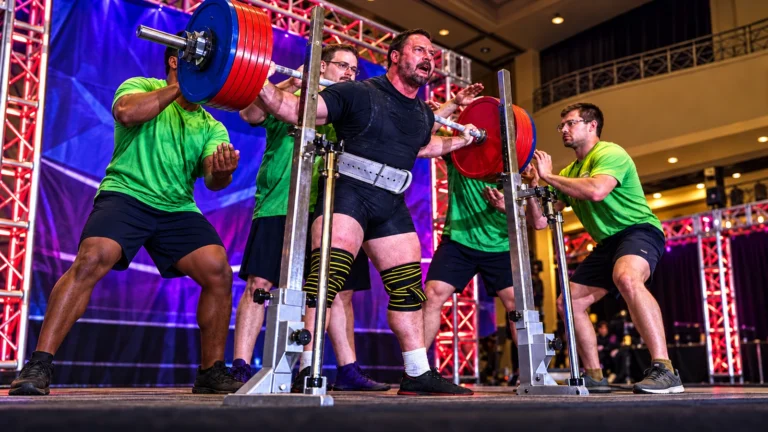 Archival source image of Dale McLaren standing with a loaded squat bar and spotters